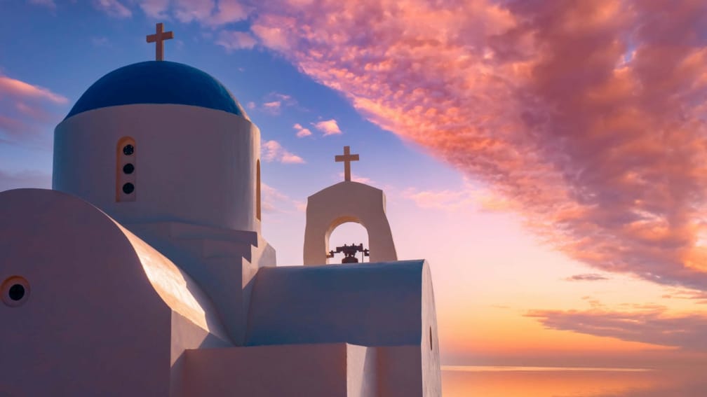 A church building with a round blue roof. A red sky is in the background.