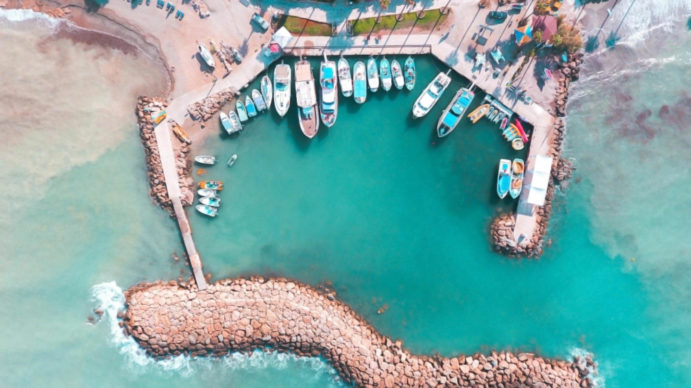 A birds eye view photo of a harbour, with boats and a rocky platform