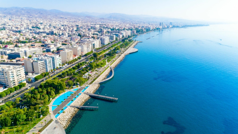 A high angle image of the island next to the sea. Buildings and a walkway are on the island.