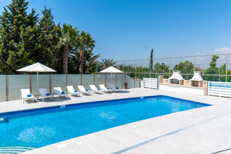 Exterior of one of Ezoria villas in Cyprus showing the private pool with sun loungers and umbrellas and two in-built barbeques