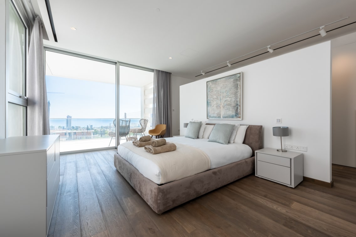 Bedroom interior showing the neutral colour-tones on the room and bed plus the sea view terrace at one of Ezoria luxury villas in Cyprus
