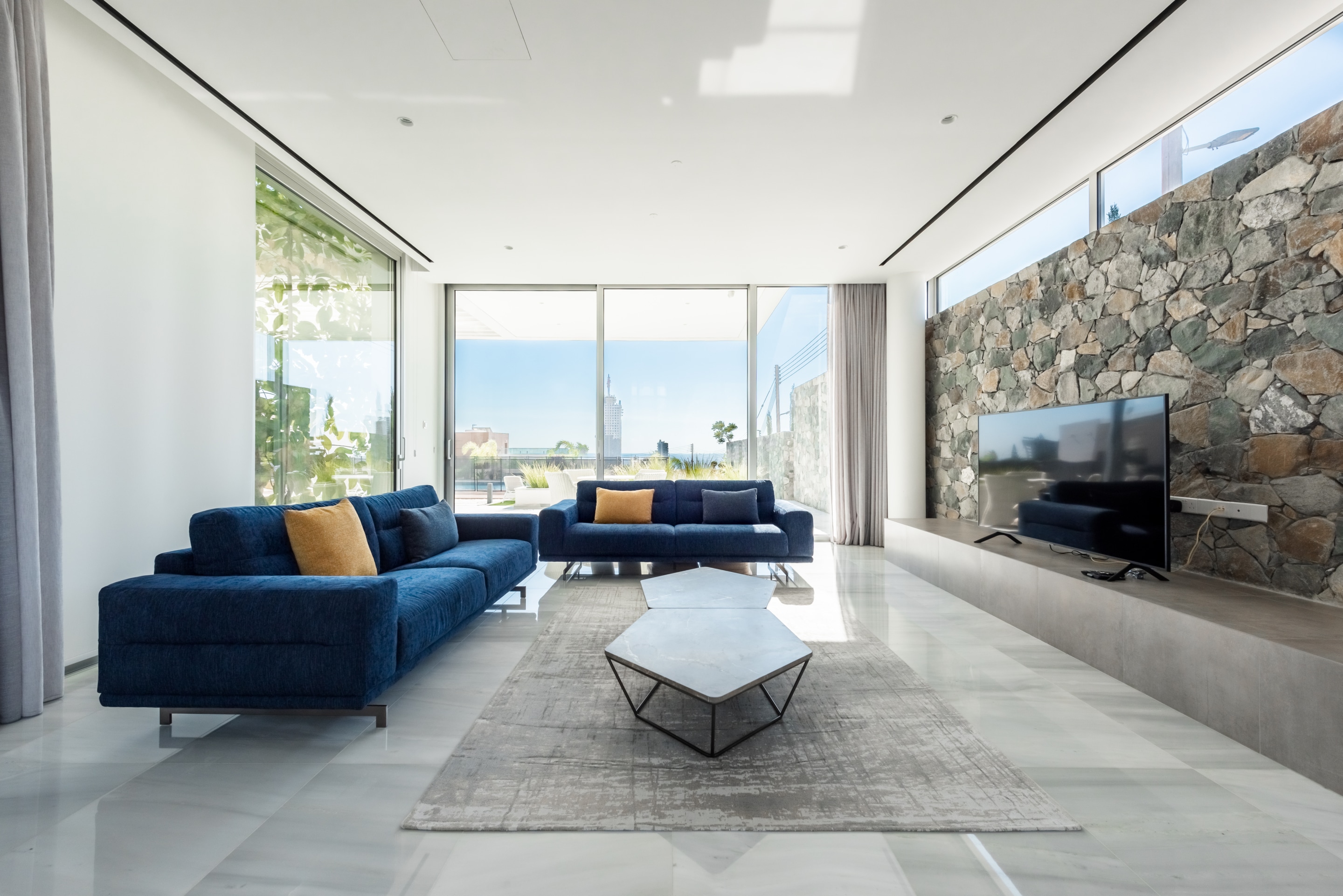 The bright and modern interiors of a living room with tall, glass pane windows at one of Ezoria villas in Cyprus
