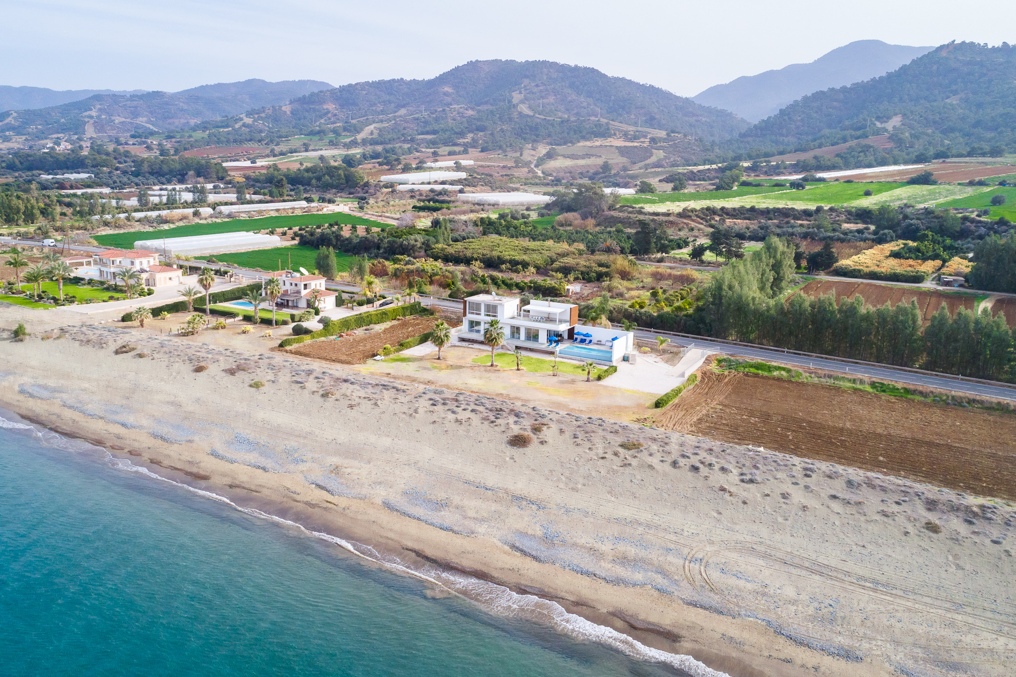 Landscape view of the sea, the beach, with the island and mountains in the background.