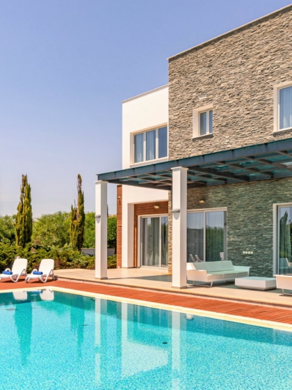 A photo of the outside of a villa, with a swimming pool out the front and an outdoor shower.