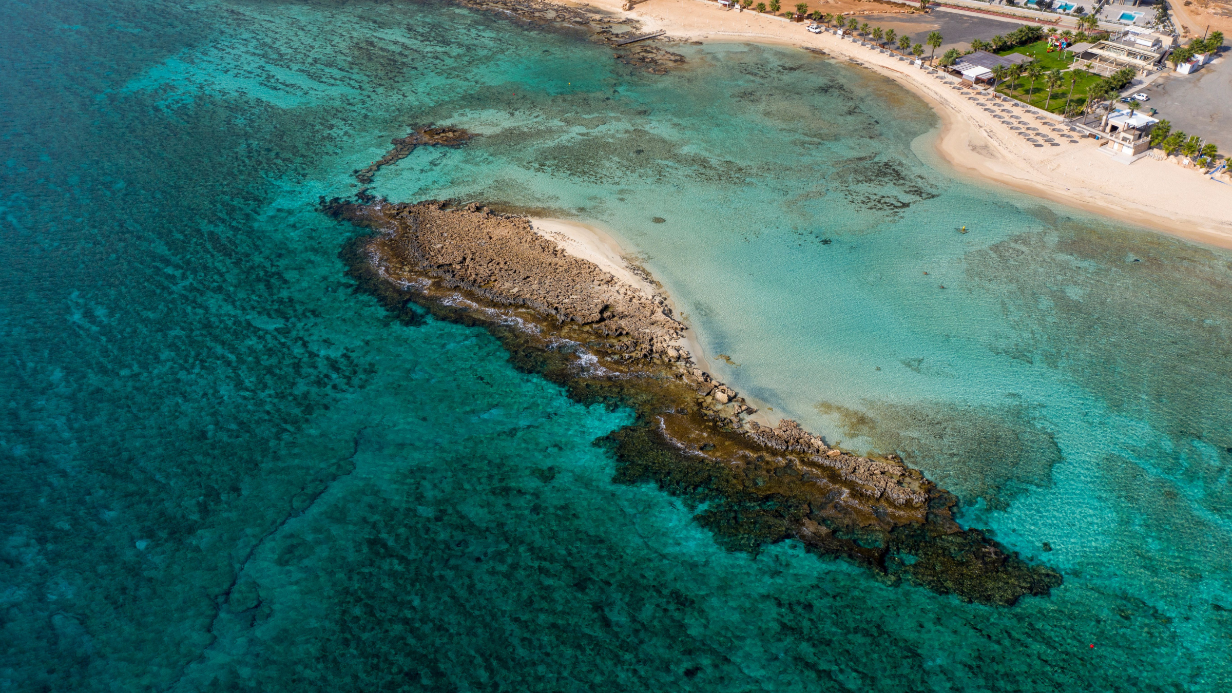 A high angle photo of the sea. In the middle there is a bit of a land with a beach.